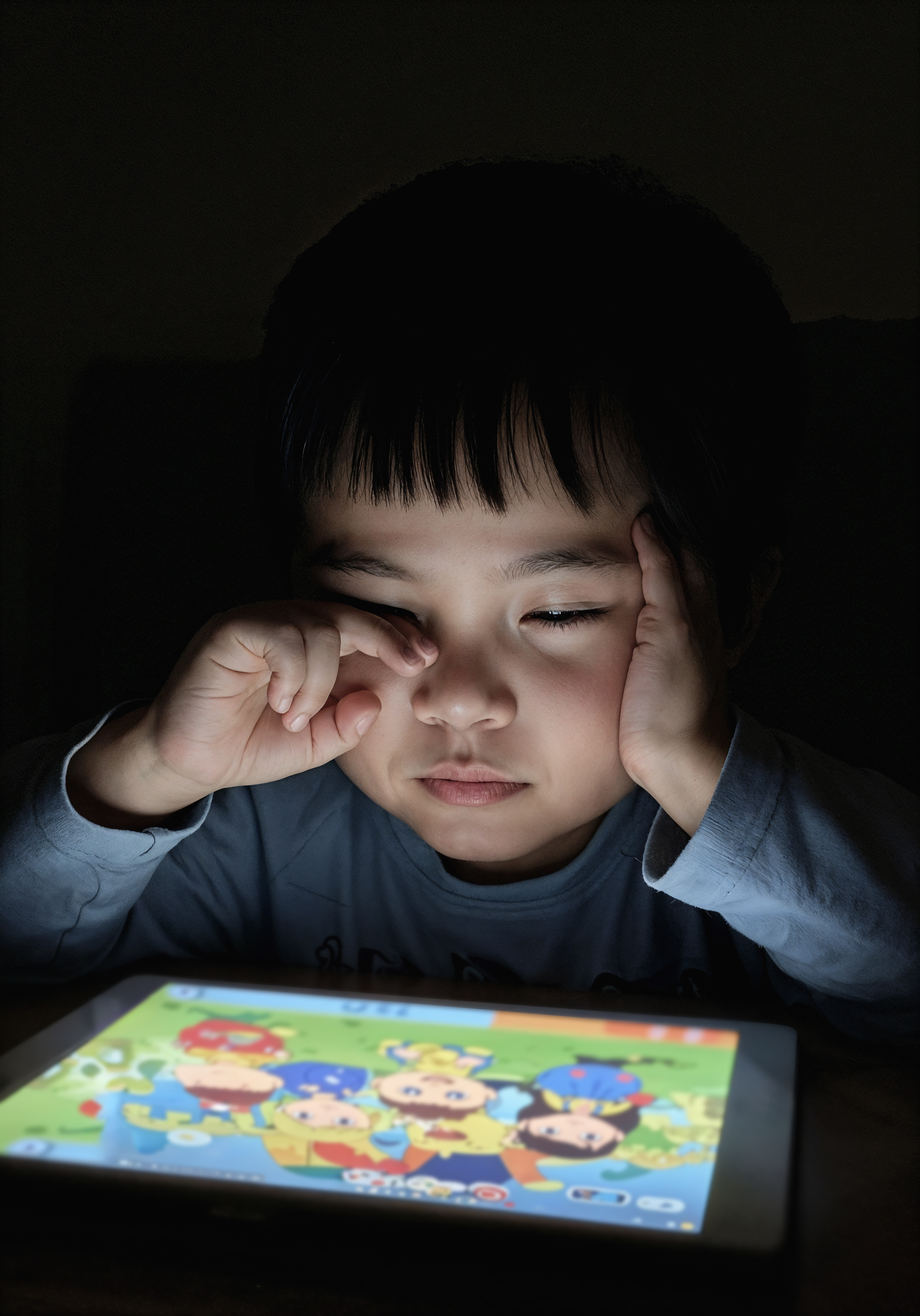 tired child playing tablet night